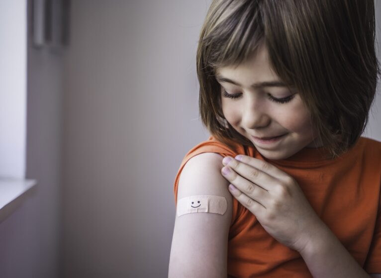 Happy child gets vaccines and smiley bandaid