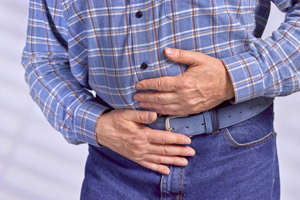 A man holds his abdominal area with his hands in pain