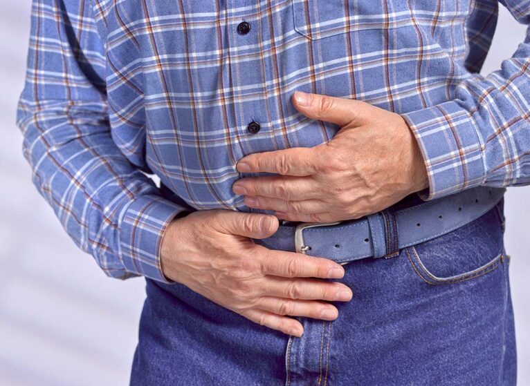 A man holds his abdominal area with his hands in pain